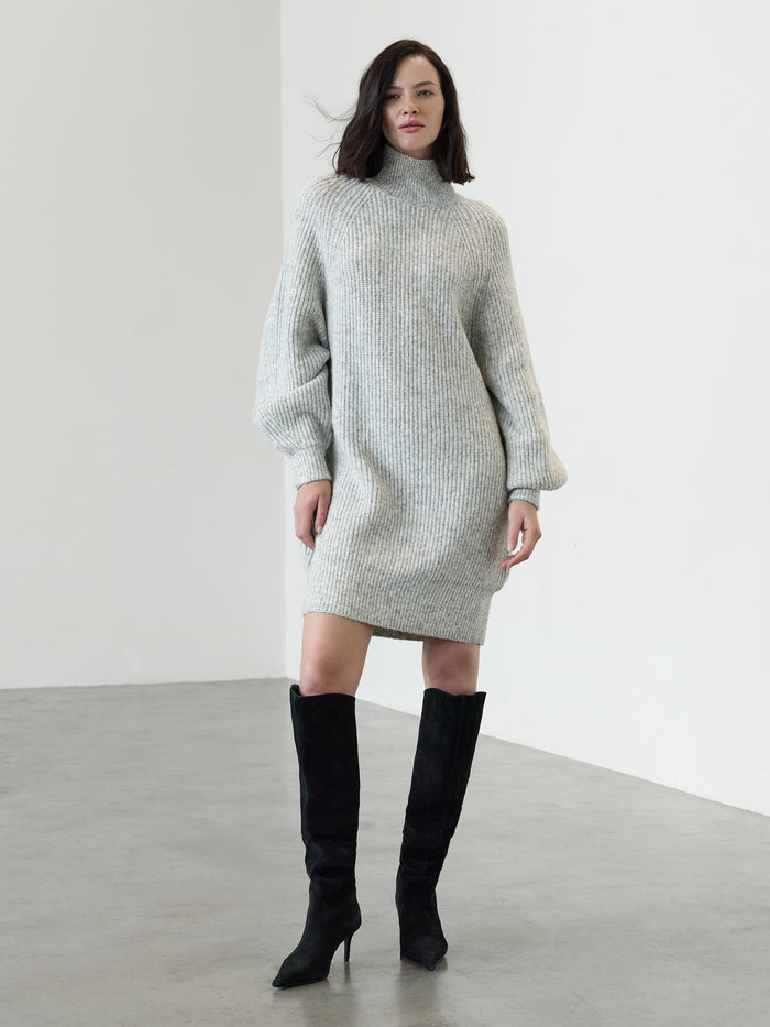 A woman wearing a mini-length grey knit Dress with a ribbed funnel neck, long sleeves and a relaxed fit.
