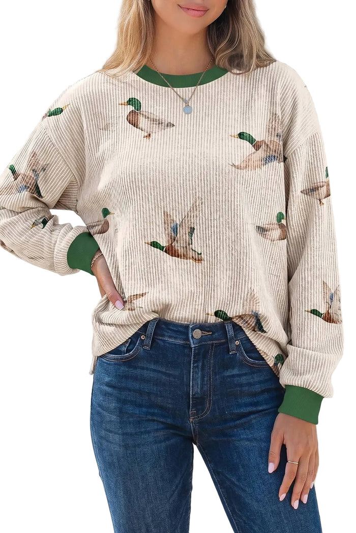 Person wearing a beige sweater with duck pattern and blue jeans outdoors.