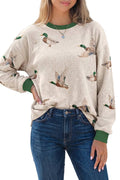 Person wearing a beige sweater with duck pattern and blue jeans outdoors.