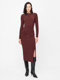 A woman wearing a burgundy midi length Dress with padded shoulders, long sleeves, a crew neckline, draped detailed waist, back keyhole fastening and a side split.